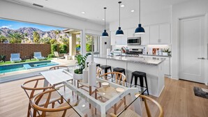 A modern kitchen with a central island, bar stools, and pendant lighting.