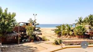 A beachside property with a thatched-roof structure, palm trees, and a clear view of the ocean. - Inigualable Suite, dos recamaras frente a Zicatela (Brisas de Zicatela)