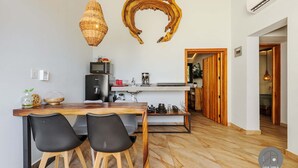 A modern kitchen with a wooden table and chairs, a hanging light fixture, and a unique wall art piece. - Inigualable Suite, dos recamaras frente a Zicatela (Brisas de Zicatela)
