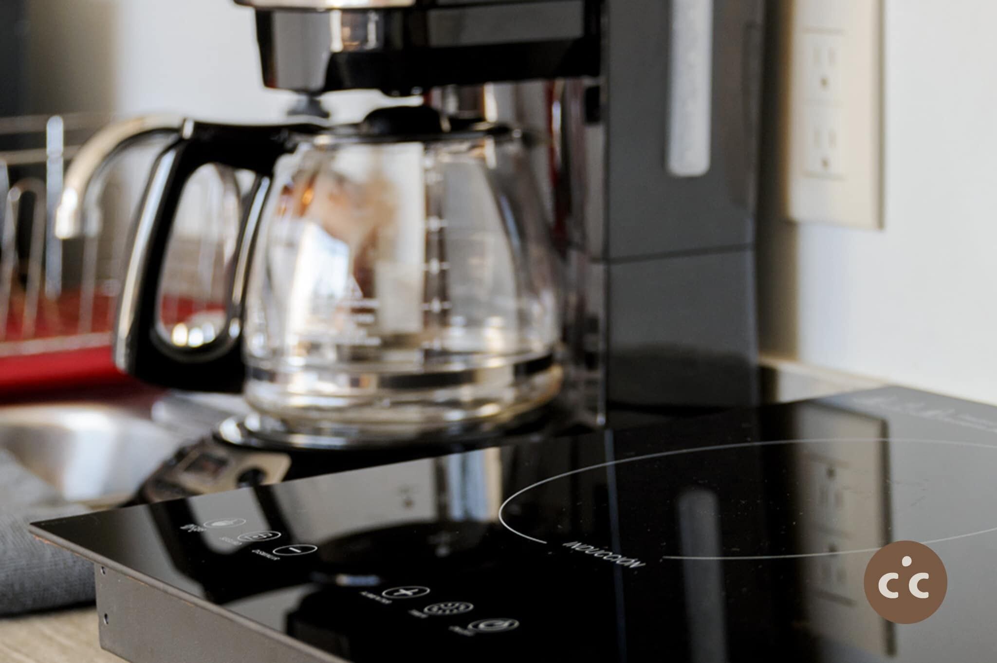 Een koffiezetapparaat met glazen kan op een modern aanrecht.