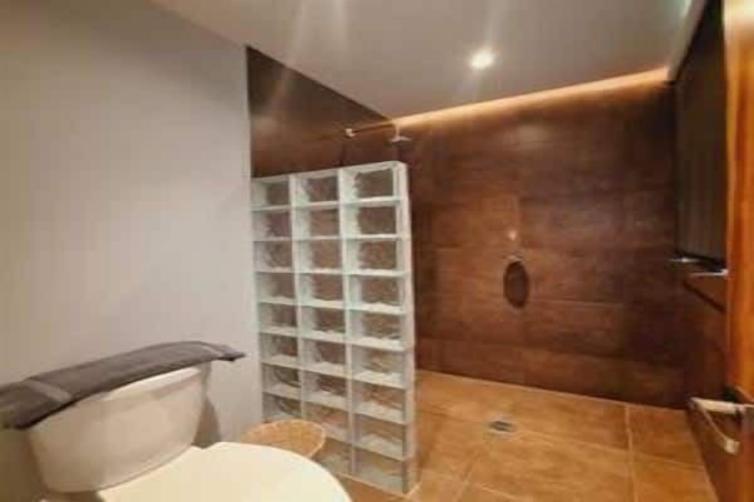 A bathroom with a toilet, a shower, and a storage unit.