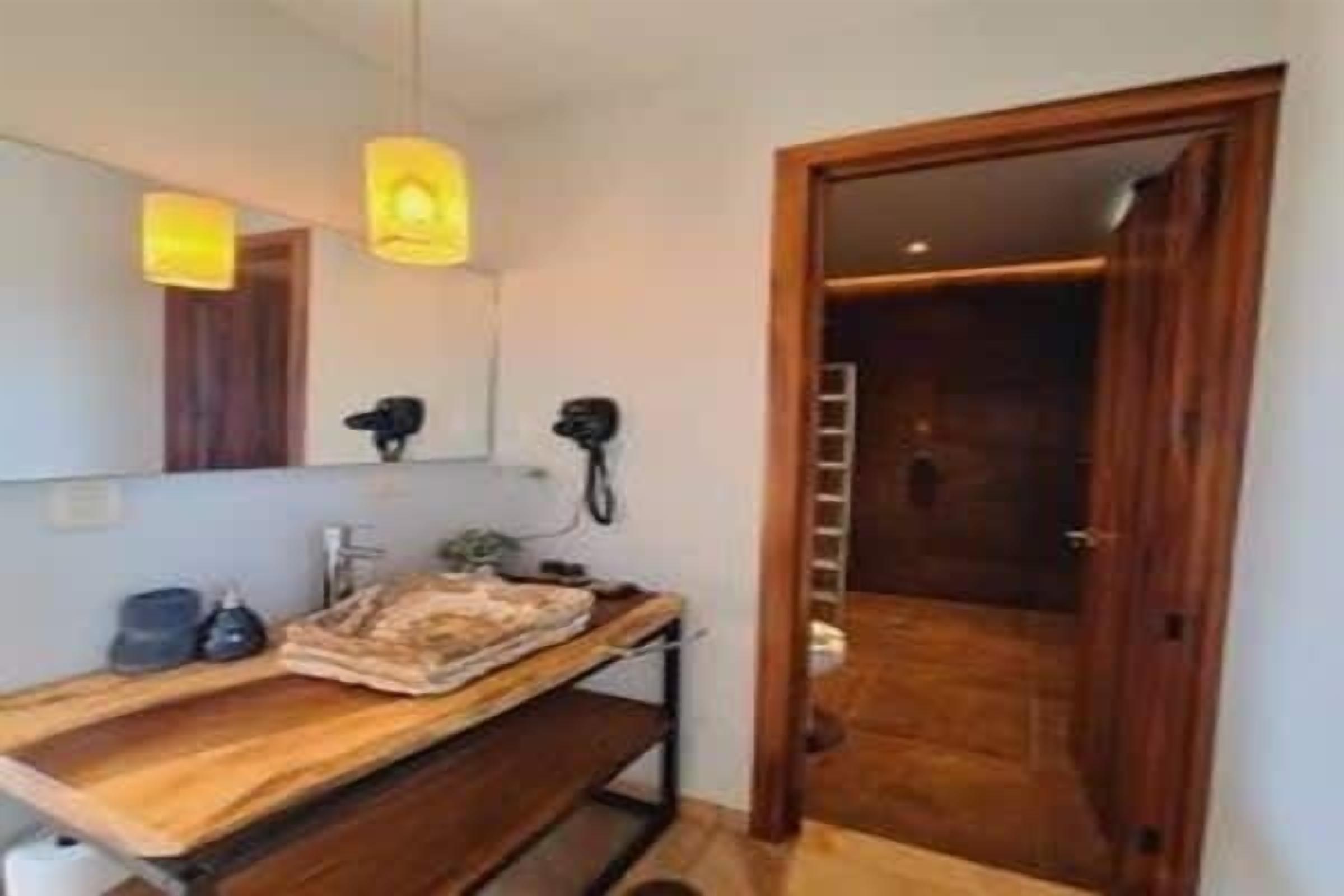 Une salle de bain avec un meuble-lavabo en bois, un miroir, un sèche-cheveux et une serviette.