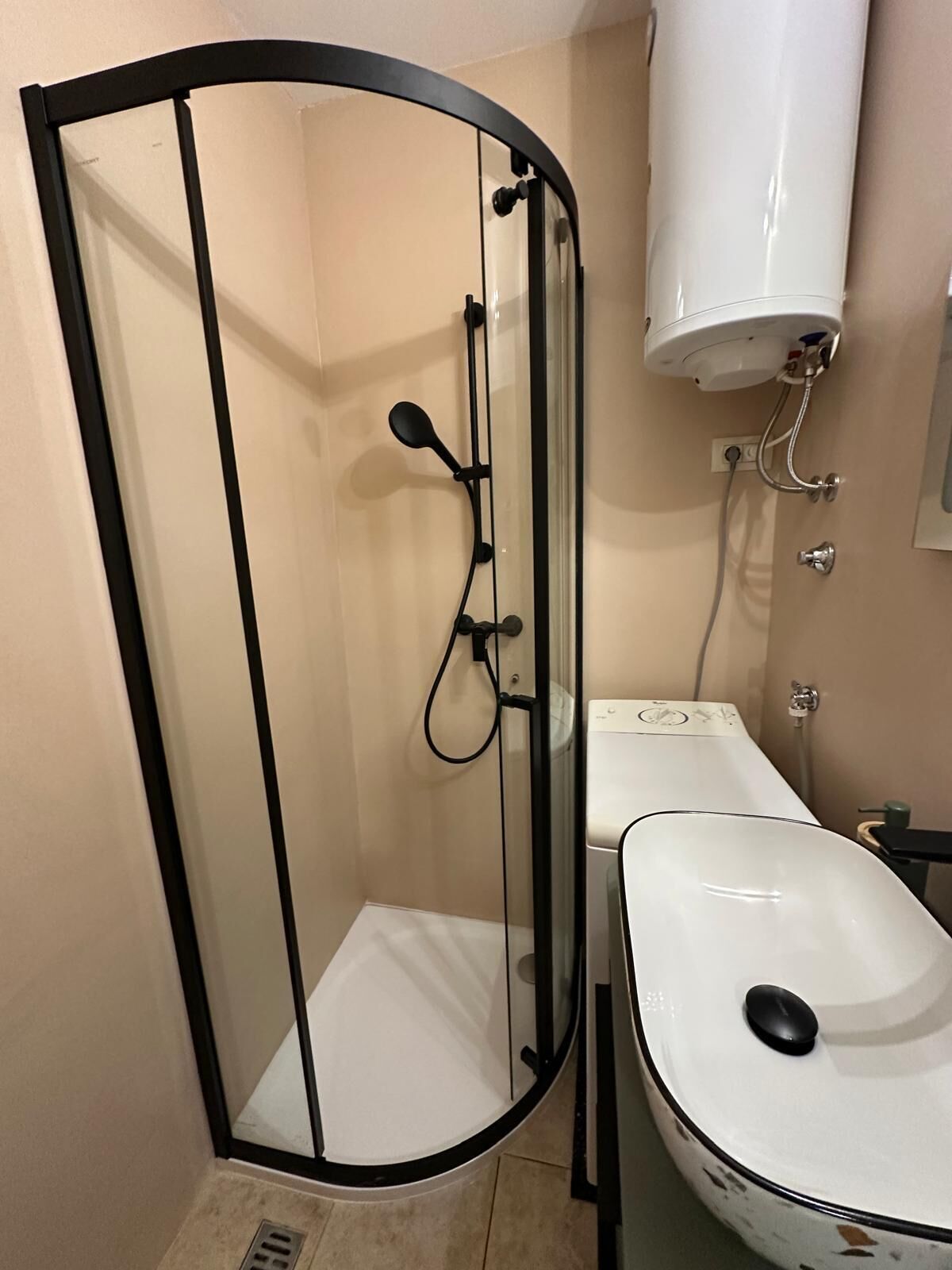 A bathroom with a glass-enclosed shower, a white sink, and a toilet.