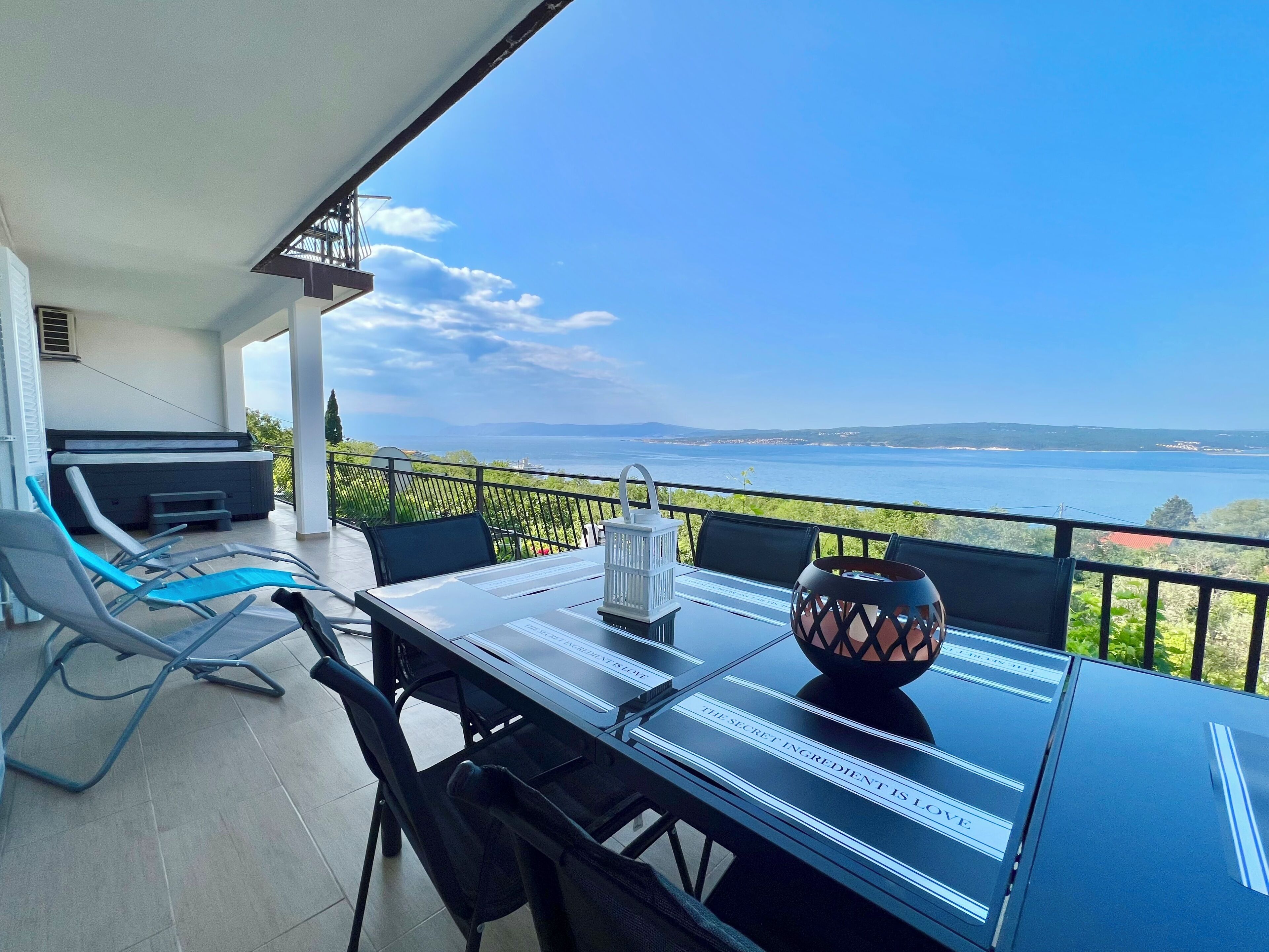 Un balcón con una mesa, sillas y vista al mar.