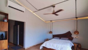 Un dormitorio amplio con una cama grande, un ventilador de techo y un equipo de aire acondicionado.