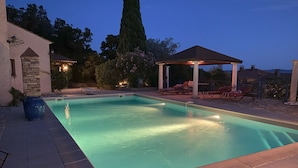 A rectangular swimming pool with a tiled deck, a stone pillar, and a pergola with chairs. - Green oasis for 2 with huge private pool + optional guest house | French Riviera (Rayol canadel sur mer)