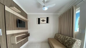 A modern living room with a sofa, TV, and built-in shelves.