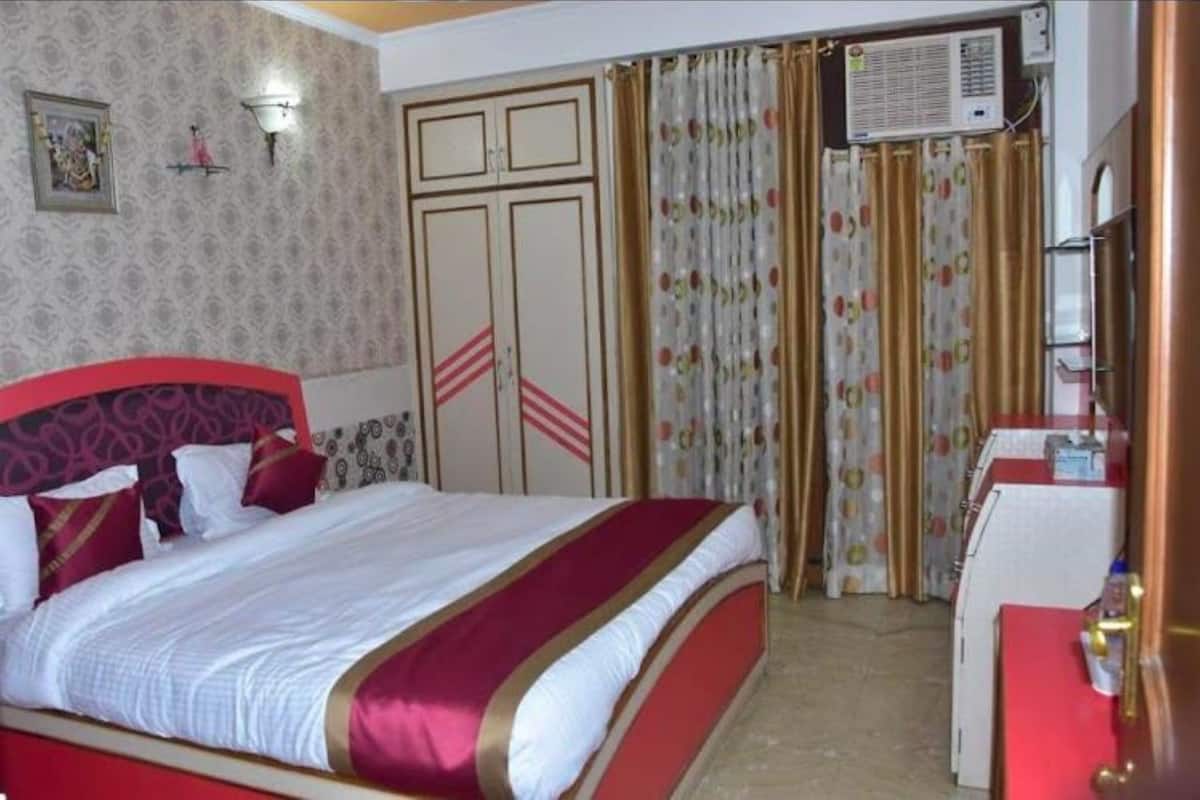 A hotel room with a bed, a desk, a wardrobe, and a curtain with a floral pattern.