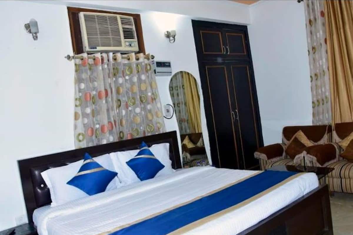 A bedroom with a bed, a wardrobe, a mirror, and a sofa.