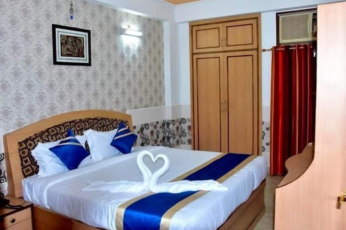 A hotel room with a bed, a wardrobe, a nightstand, and a wall-mounted light fixture.