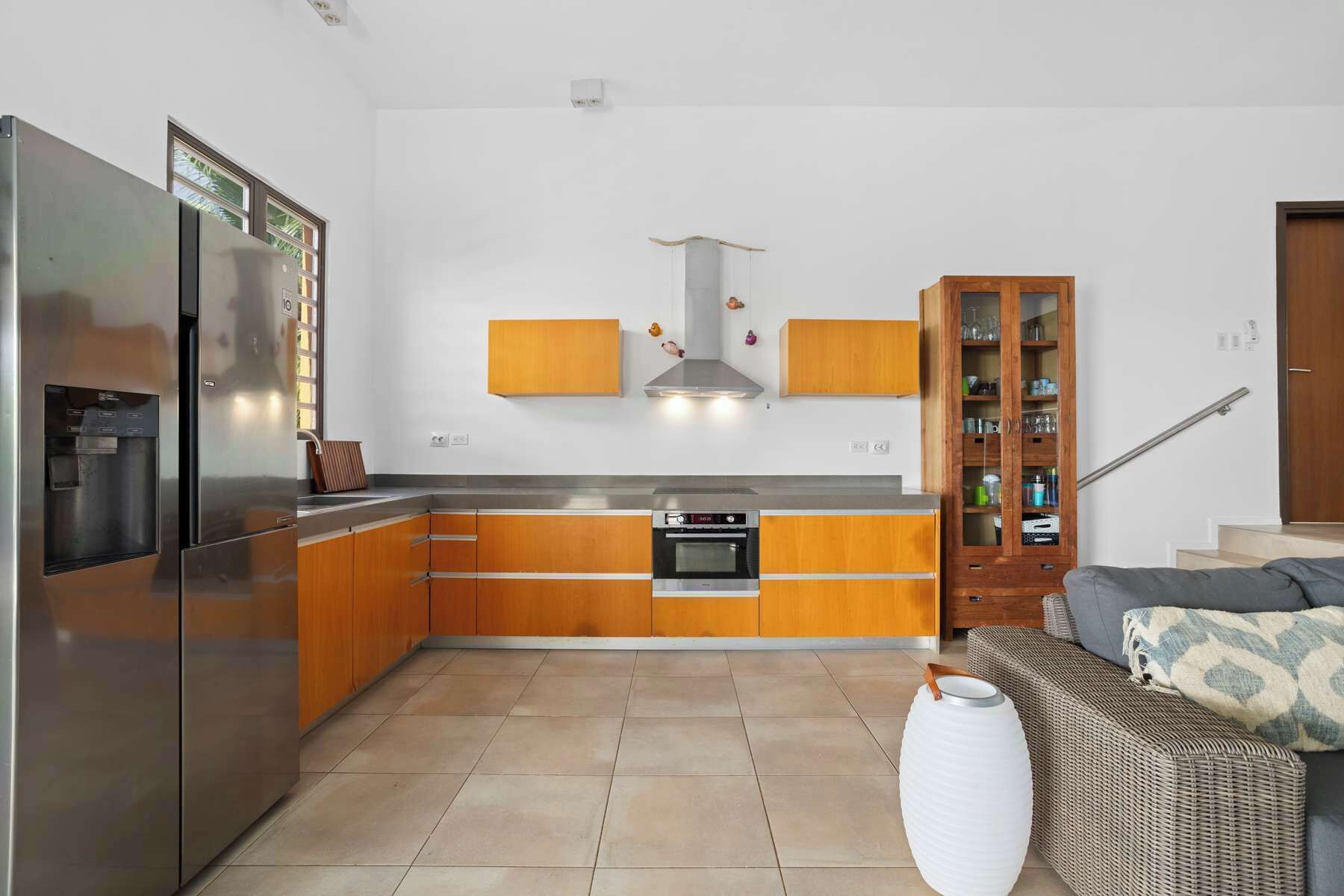 Une cuisine moderne dotée d’appareils électroménagers en acier inoxydable, de meubles en bois et d’un four encastré.