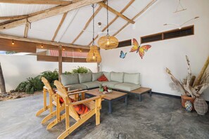 A cozy outdoor seating area with a sofa, wooden chairs, and a coffee table.