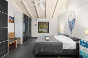A modern bedroom with a large bed, a desk, a chair, and a wardrobe.