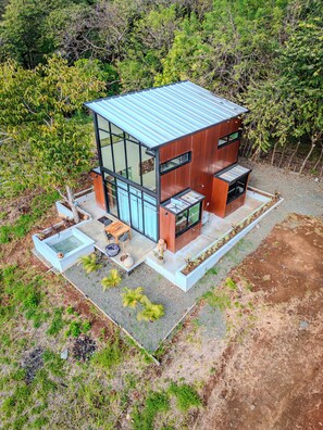 A modern house with a large glass window, a small patio, and a garden. - Kooteja Santa Catalina KAÏSA (Hicaco)