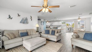 A spacious living room with a large sectional sofa, a dining area, and a kitchen in the background.