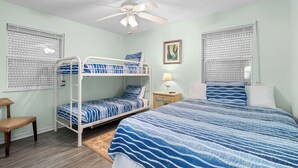 A bedroom with bunk beds, a single bed, a ceiling fan, and a nightstand with a lamp.