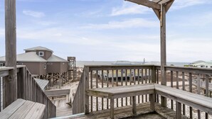 A wooden deck with a view of beach houses and a sandy beach.