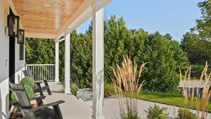 A covered outdoor seating area with chairs and a small garden.