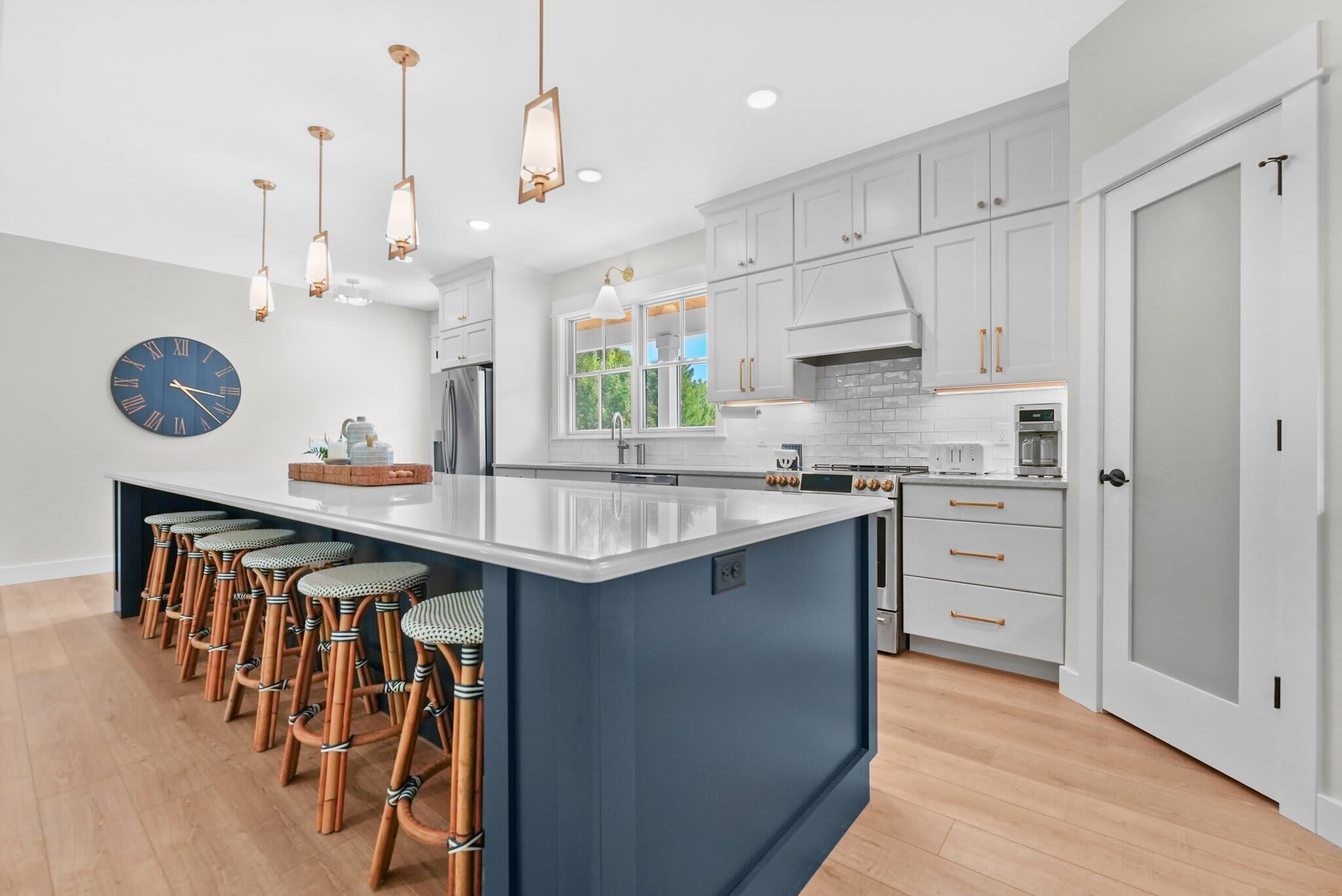 A modern kitchen with a large island, bar stools, and pendant lighting.