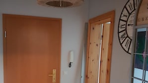 Ein Zimmer mit Holztüren, einer großen Wanduhr und einer Pendelleuchte.