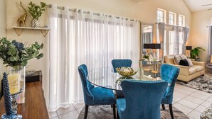 A dining area with a glass table, blue upholstered chairs, and a decorative bowl centerpiece.