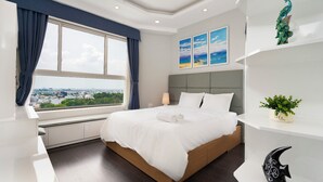 Ett modernt hotellrum med en stor säng, utsikt över staden och en dekorativ hylla med en växt och en skulptur.