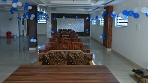 A spacious room with a long table and chairs, decorated with blue and white balloons. - Maa Tara Homestay (Rishikesh)
