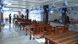 A spacious dining area with wooden tables and chairs, decorated with blue and white balloons. - Maa Tara Homestay (Rishikesh)
