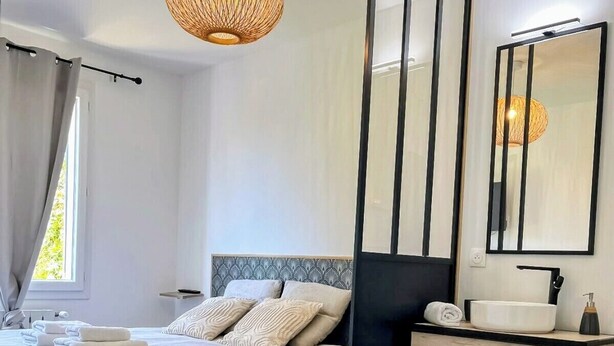 Quarto moderno com cama, mesa de cabeceira e um espelho grande.