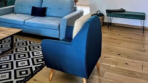 Uma sala de estar moderna com um sofá azul, um tapete estampado, uma mesa de centro de madeira e um lustre.