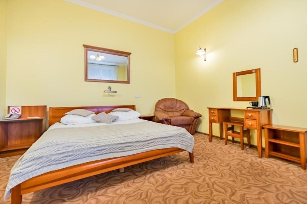 Una habitación de hotel con una cama, un escritorio, una silla y un espejo.