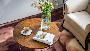 A round wooden table with a cup of coffee, a glass vase with flowers, and a magazine. - Pod Ratuszem (Rzeszów)