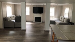 Amplia sala de estar con chimenea, televisor y dos sofás.