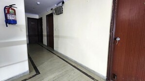 A hallway with a fire extinguisher, a door, and a ceiling light fixture. - Hotel Mid Town (New Delhi)