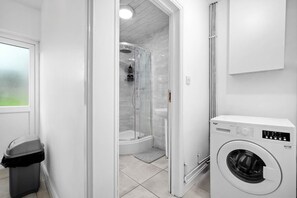Une salle de bain moderne dotée d’une douche à parois de verre, de toilettes intégrées et d’un lave-linge à chargement frontal.