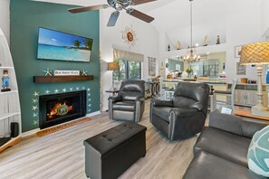 Una sala de estar con chimenea, sillones de cuero, televisor y comedor.