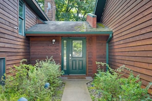 Une maison en bois avec une porte verte et un petit porche.