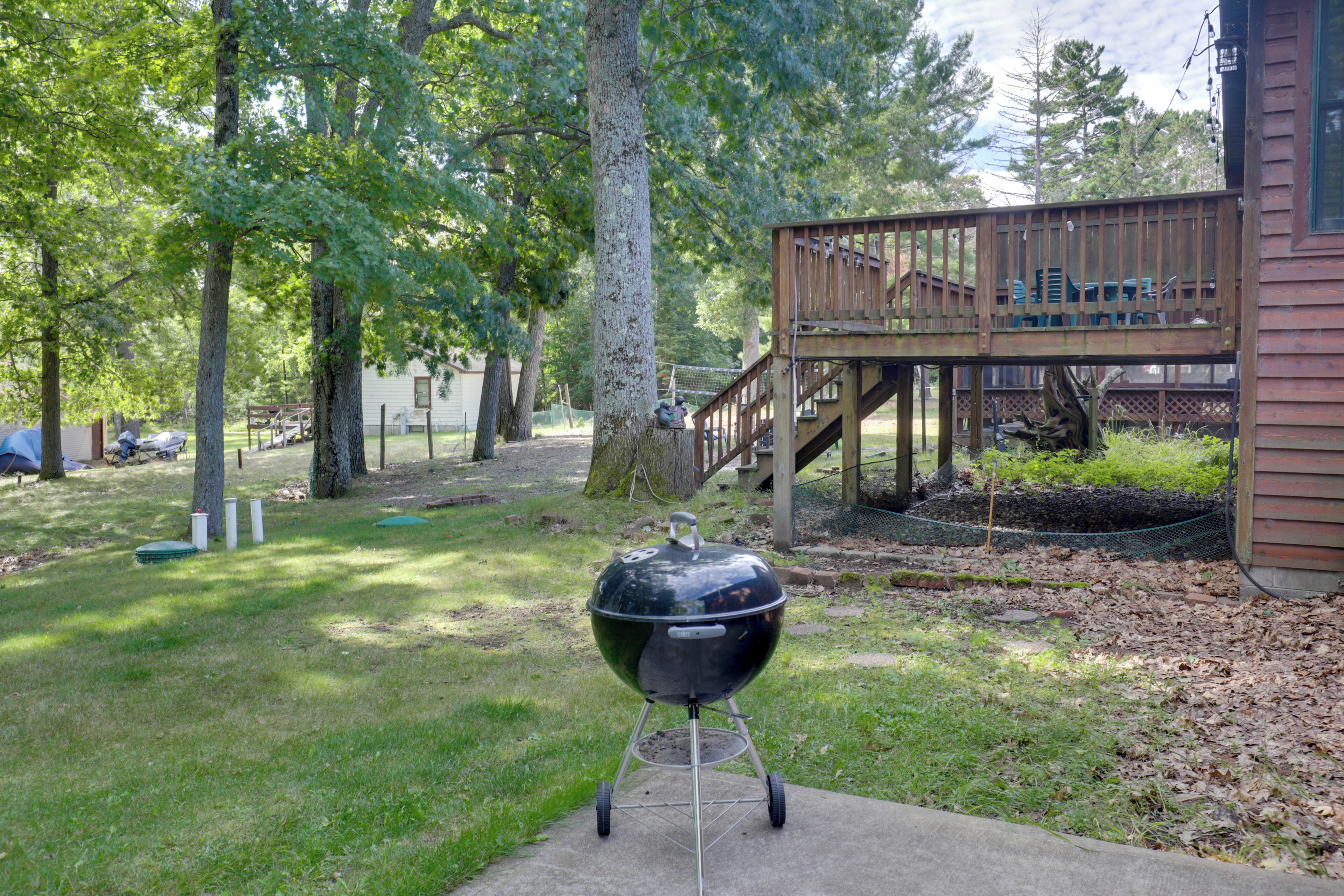 Un patio trasero con una parrilla, una terraza de madera y una casa.