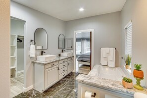 A modern bathroom with a vanity, double sink, and a bathtub.