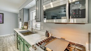 Una cocina moderna con electrodomésticos de acero inoxidable, gabinetes verdes y una isla grande con estufa integrada.