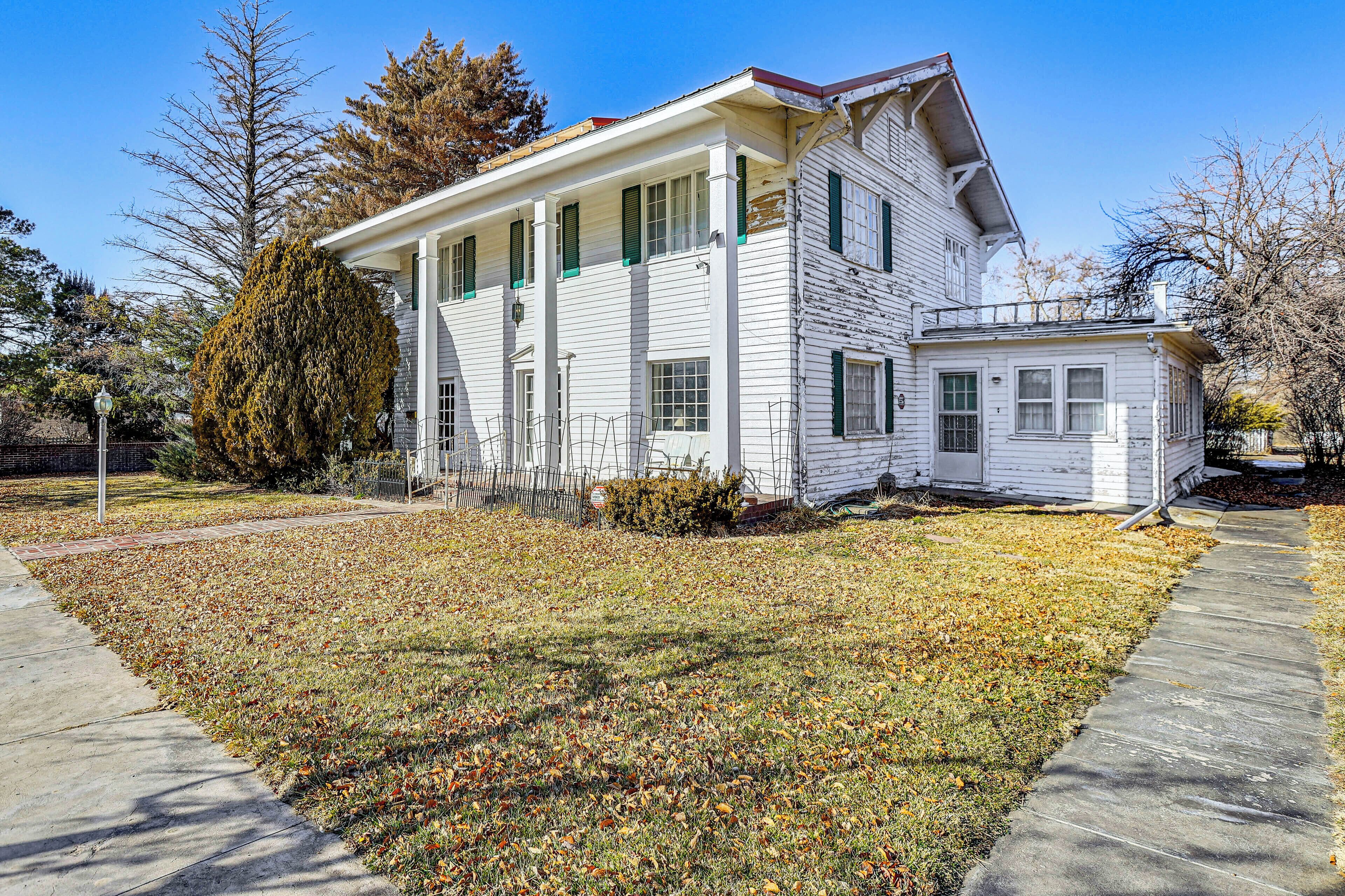 A two-story white house with a front porch and a small attached garage.