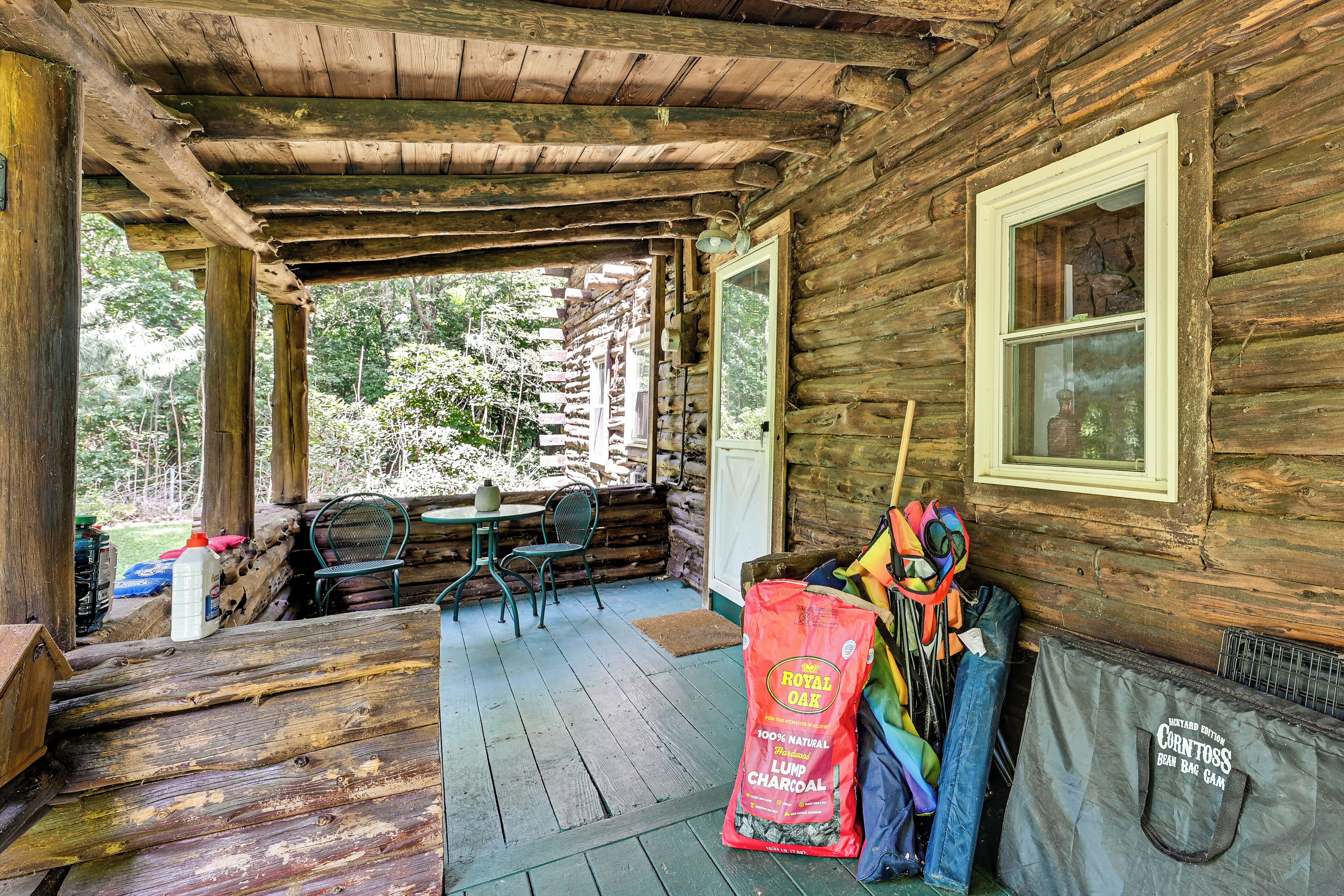 A rustic cabin with a porch, wooden walls, a window, and outdoor seating.