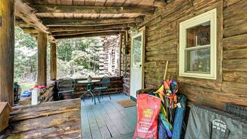 A rustic cabin with a porch, wooden walls, a window, and outdoor seating.