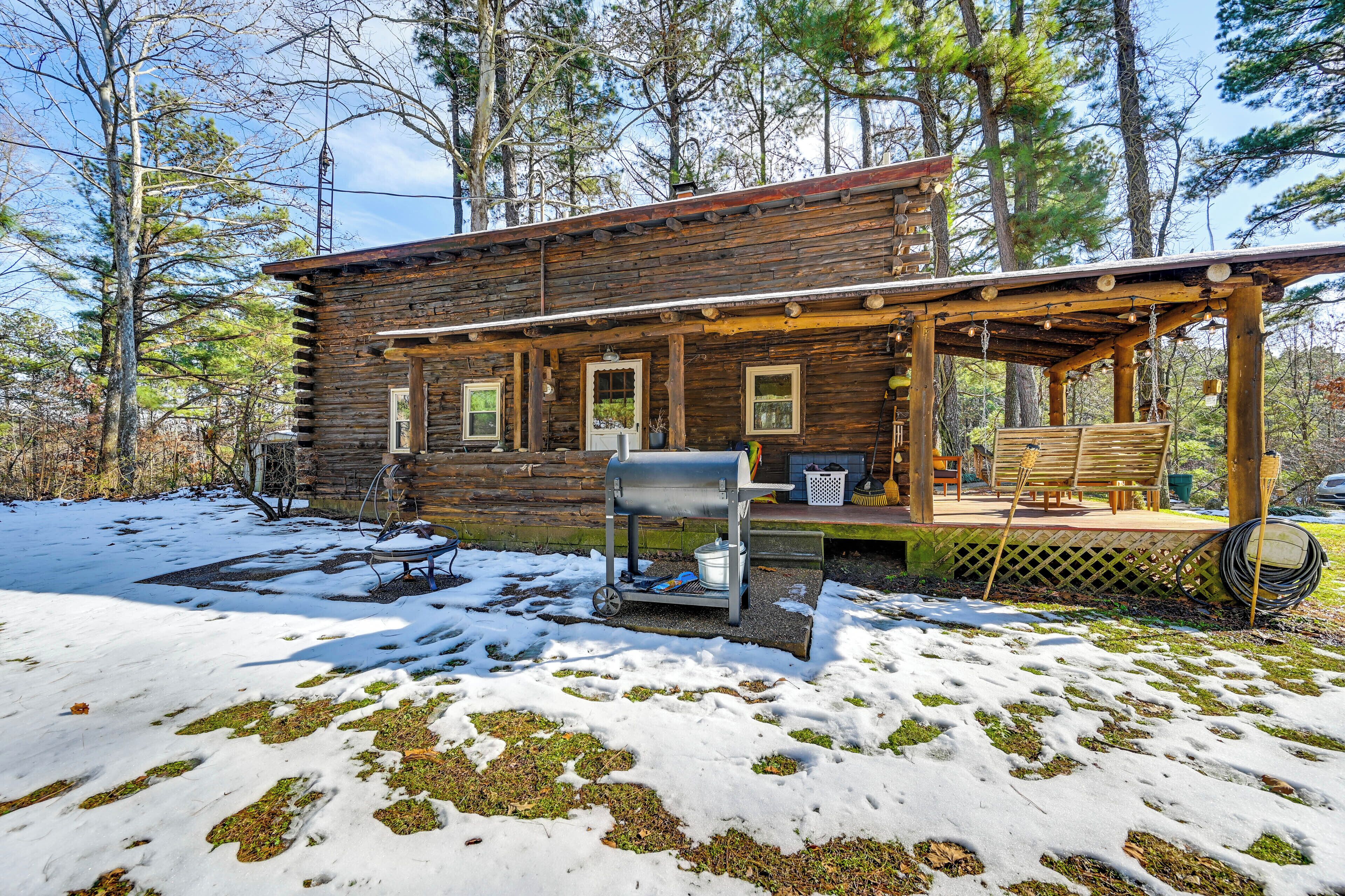 A rustic cabin with a porch, a grill, and outdoor seating.