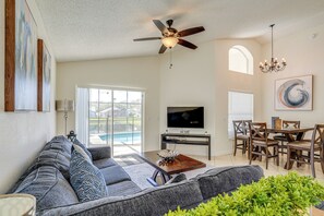 A living room with a sofa, TV, ceiling fan, dining table, and chairs. - 9 Mi to Disney: Home w/ Pool Table & Water Views! (Kissimmee)