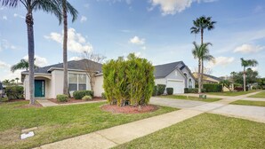 A residential neighborhood with houses, palm trees, and a well-maintained lawn. - 9 Mi to Disney: Home w/ Pool Table & Water Views! (Kissimmee)