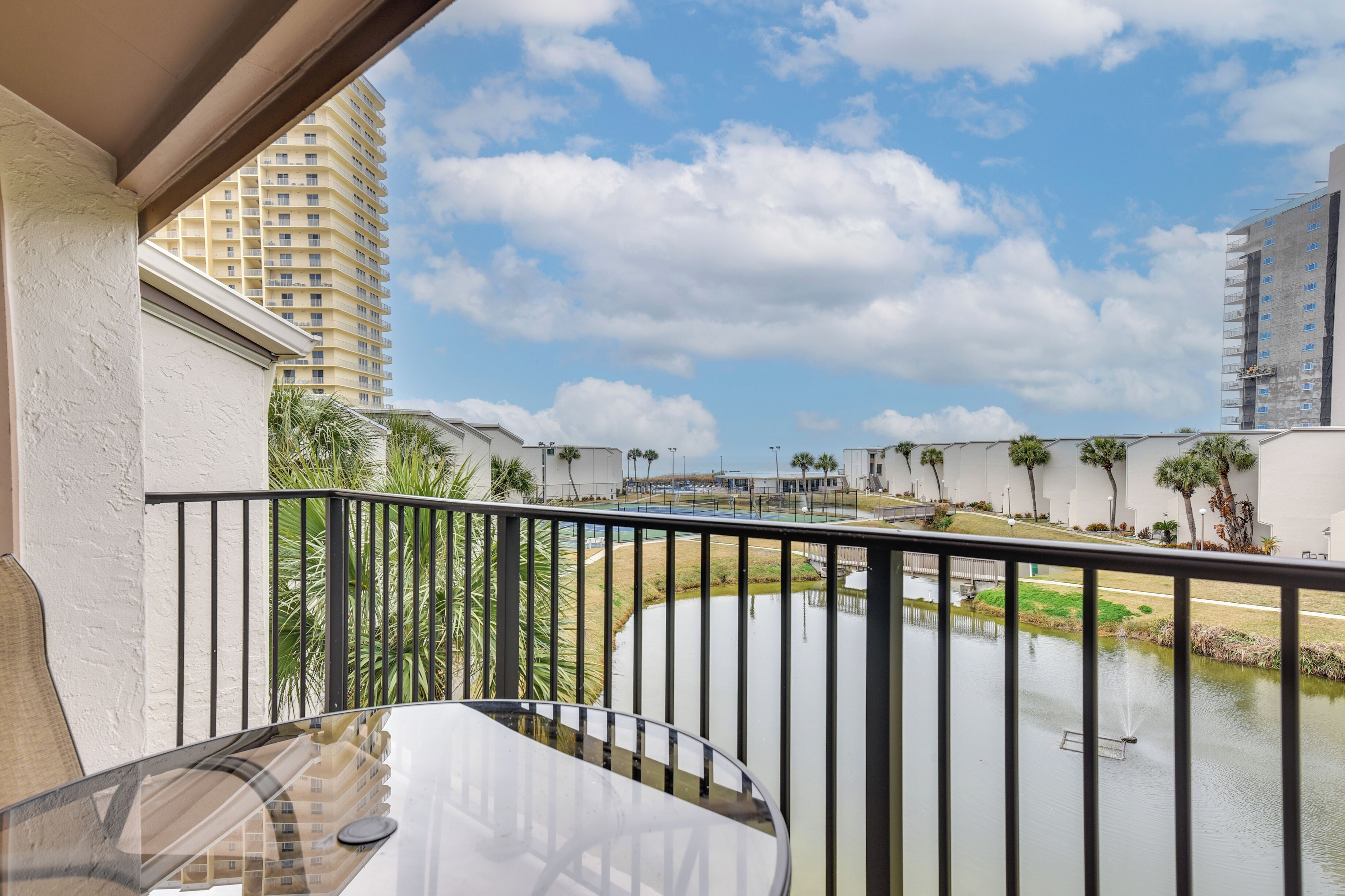 A balcony with a view of a water feature and a tall building in the background.