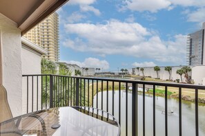 A balcony with a view of a water feature and a tall building in the background.