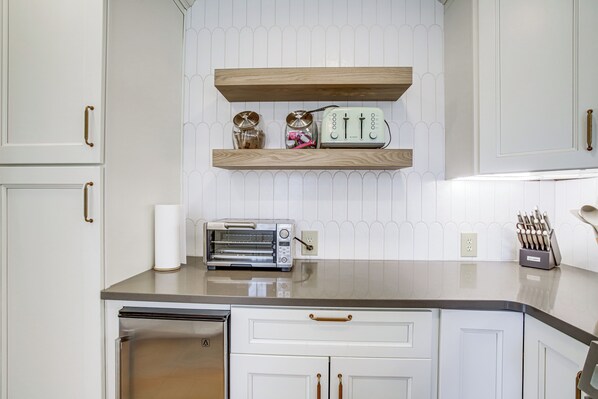 A kitchen with white cabinetry, a stainless steel refrigerator, a toaster, and a knife block on the countertop. - Riverfront Gem w/ Fire Pit in Eden (Eden)