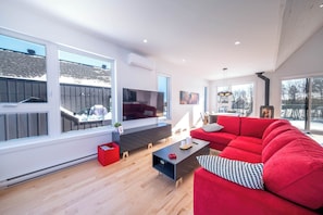 Una sala de estar moderna con un sofá rojo, un televisor de pantalla plana y una chimenea.